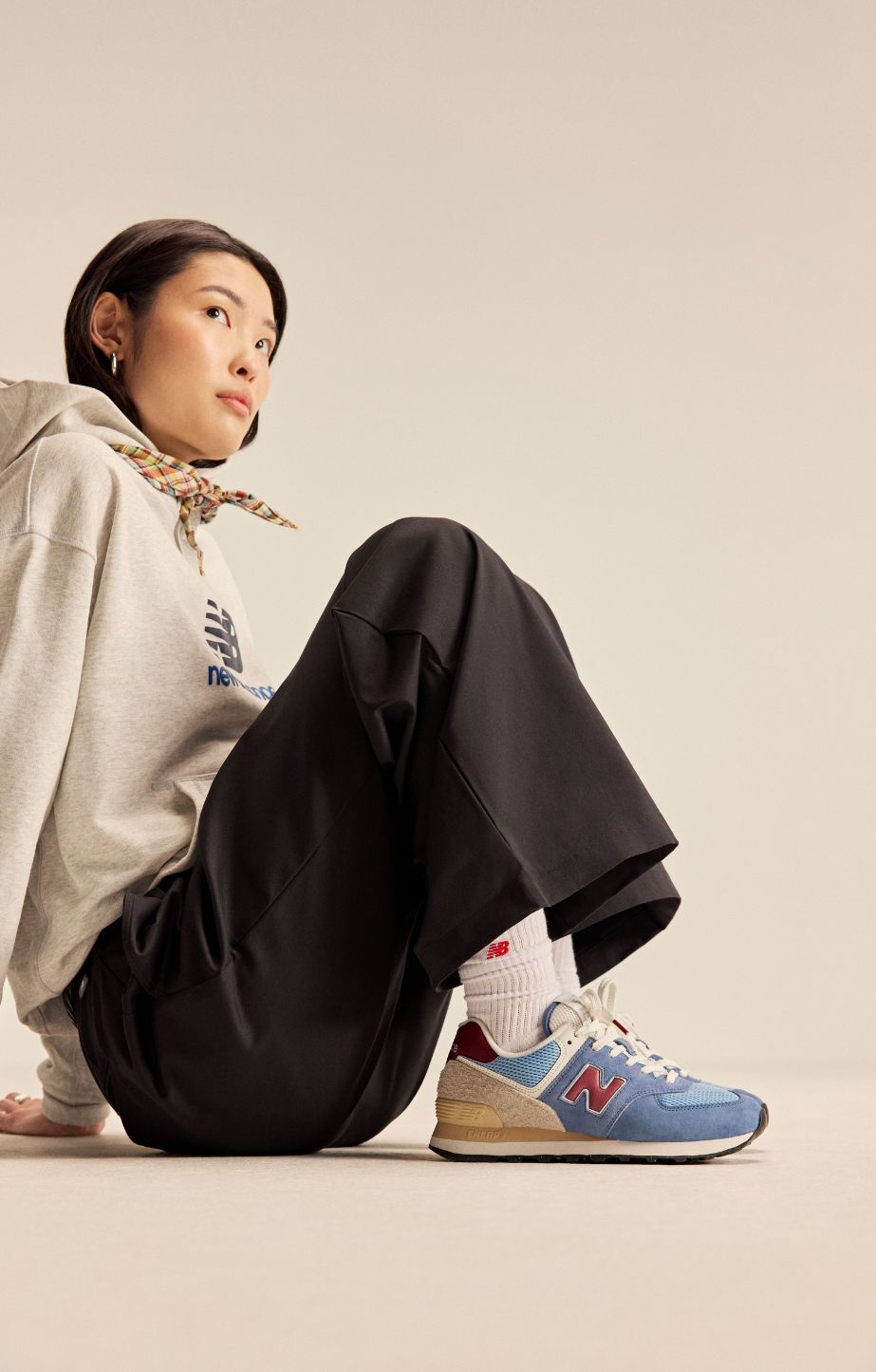 woman sitting on the group wearing new balance 574 sneakers